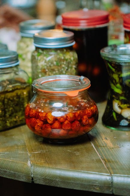 Colorful assorted pickled jars displayed on a rustic wooden table, showcasing vibrant food preservation.